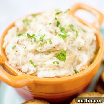 Onion dip in a orange bowl next to crackers