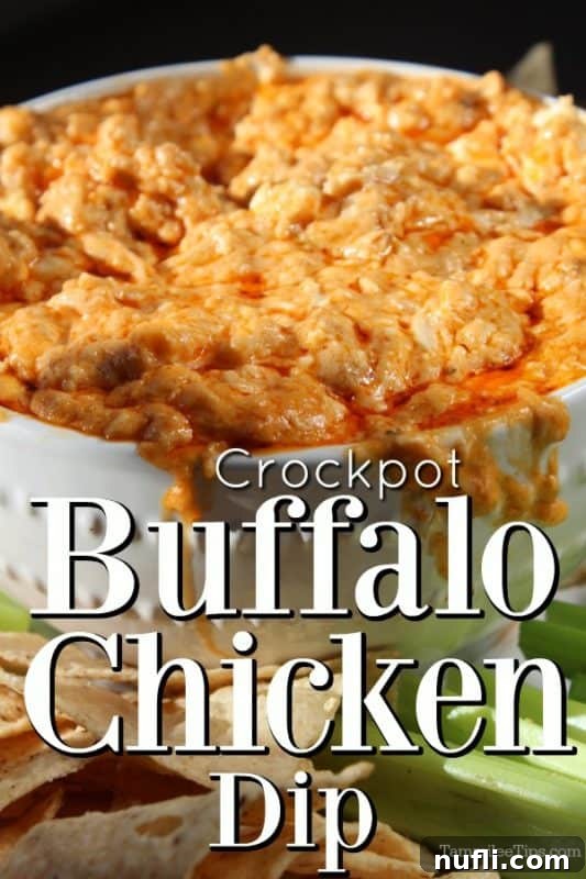 Crockpot Buffalo Chicken Dip in a white bowl overflowing with dip, next to chips and celery
