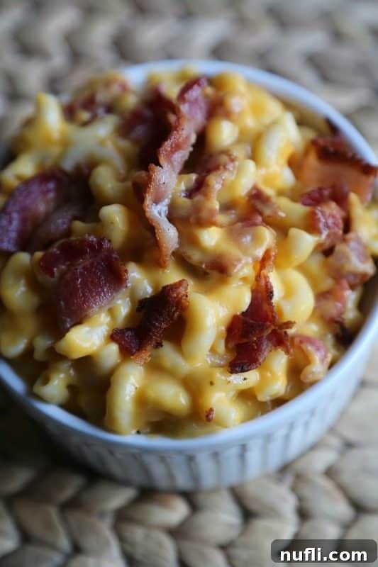 Close-up shot of creamy Bacon Mac and Cheese served in a pristine white bowl, showcasing the rich texture and bacon pieces.