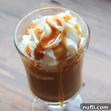 Caramel latte in a glass mug garnished with whipped cream and caramel