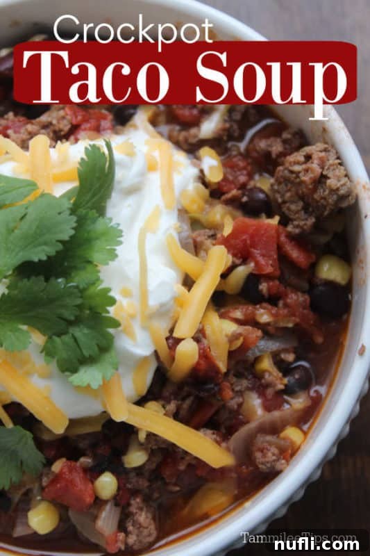 Crockpot Taco Soup served in a white bowl, garnished with a dollop of sour cream and shredded cheese
