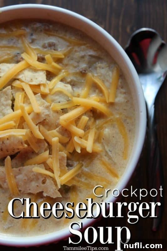 Hearty Crockpot cheeseburger soup in a white bowl, ready to be enjoyed with a silver spoon.