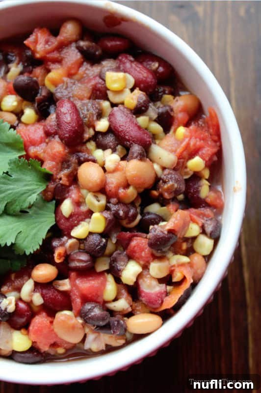 A top-down view of a vibrant Crock Pot Vegetarian Three Bean Chili, showcasing its colorful ingredients.