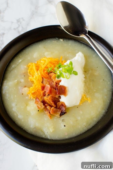 creamy potato soup in a dark bowl with a spoon resting on the bowl