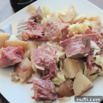 Crockpot Guinness corned beef and cabbage with potatoes on a white plate
