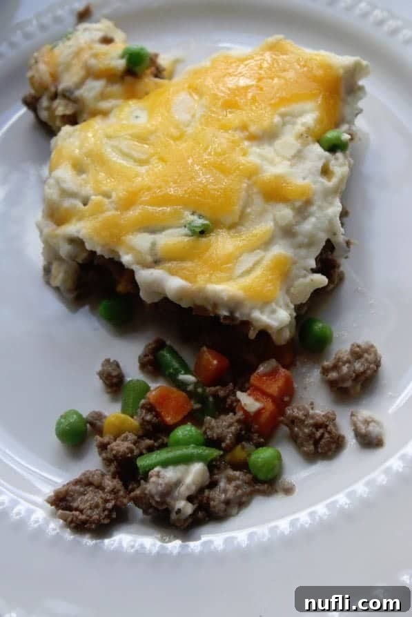 A perfectly portioned serving of Shepherd's Pie on a white plate, showcasing the distinct layers of meat and potato.