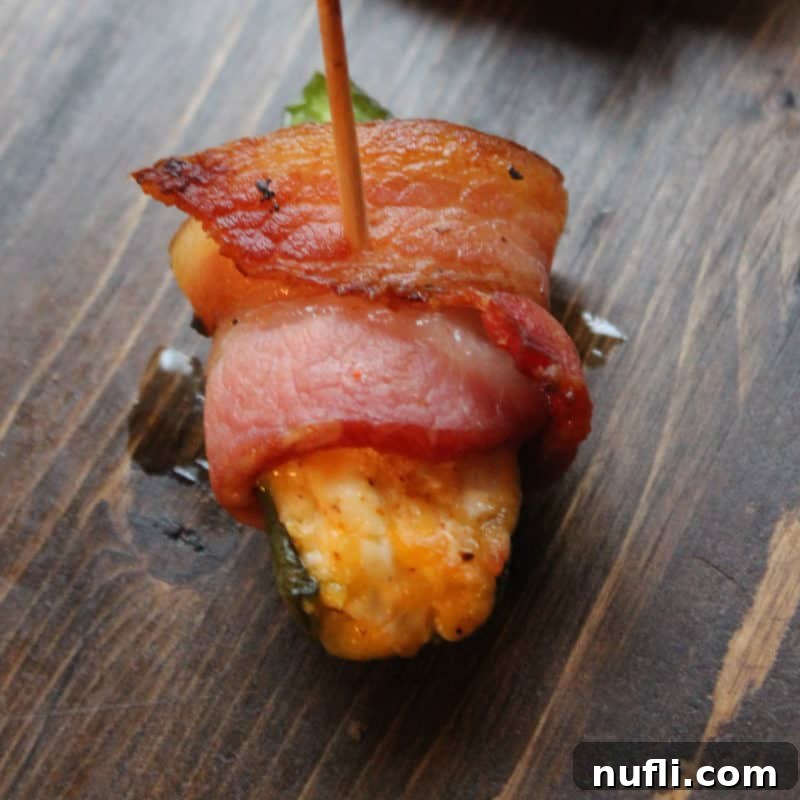 Effortless Entertaining: Simple Finger Foods for Any Party 25 Juicy Bacon-Wrapped Jalapeños, held together with a toothpick, on a rustic wood board, showcasing their vibrant colors and savory appeal.