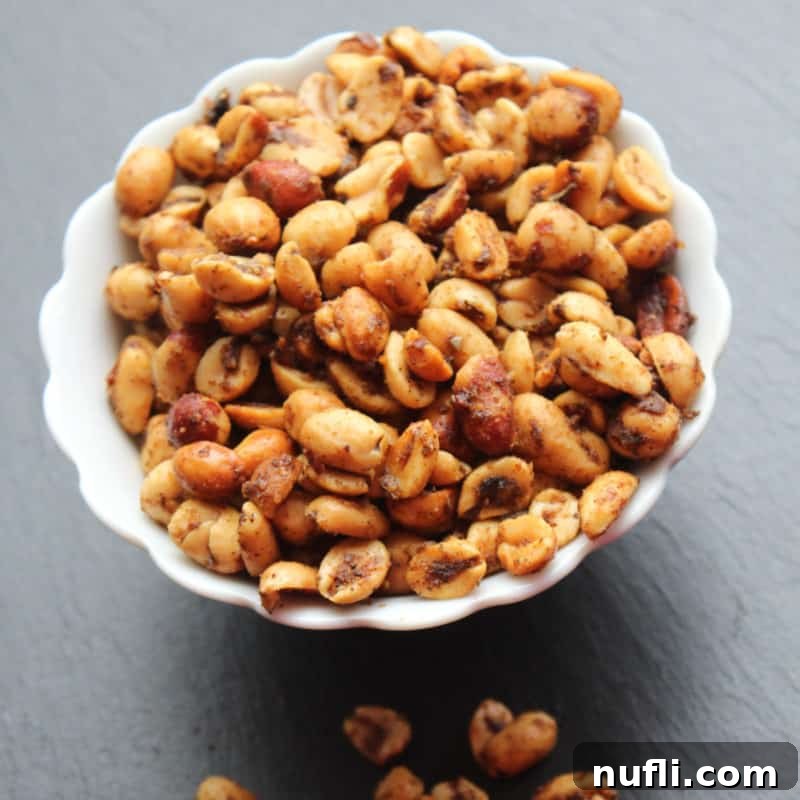 Effortless Entertaining: Simple Finger Foods for Any Party 31 Spicy Peanuts in a white bowl with a few scattered below, showcasing their zesty coating and inviting crunch.
