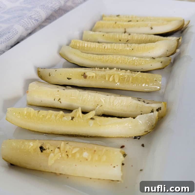 Effortless Entertaining: Simple Finger Foods for Any Party 8 Crisp green Ranch Pickles lined up on a white platter with a cloth napkin in the background, showcasing their unique coating.