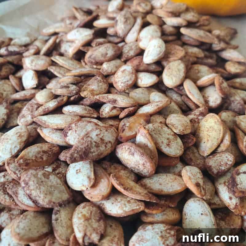 Effortless Entertaining: Simple Finger Foods for Any Party 10 Golden brown Pumpkin Spice Pumpkin Seeds spread evenly on parchment paper, hinting at their sweet and spicy coating.