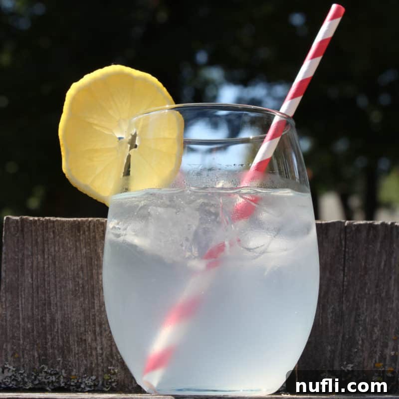 Sun-Kissed Sips: Over 35 Refreshing Summer Cocktails 11 Mango Passionfruit Lemonade cocktail in a clear glass with lemon wheel and red striped straw
