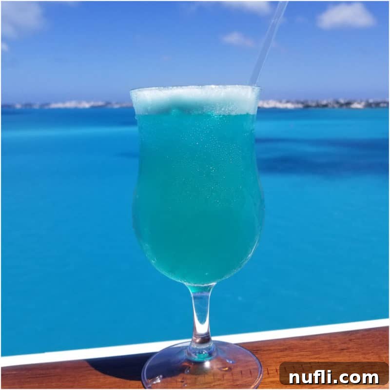 Sun-Kissed Sips: Over 35 Refreshing Summer Cocktails 20 Blue Margarita on a wood rail with the ocean behind it