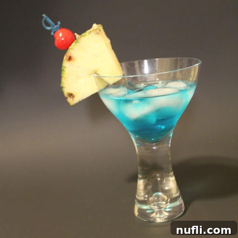 Sun-Kissed Sips: Over 35 Refreshing Summer Cocktails 24 Blue Shark cocktail with pineapple wedge and cherry garnish in a martini glass