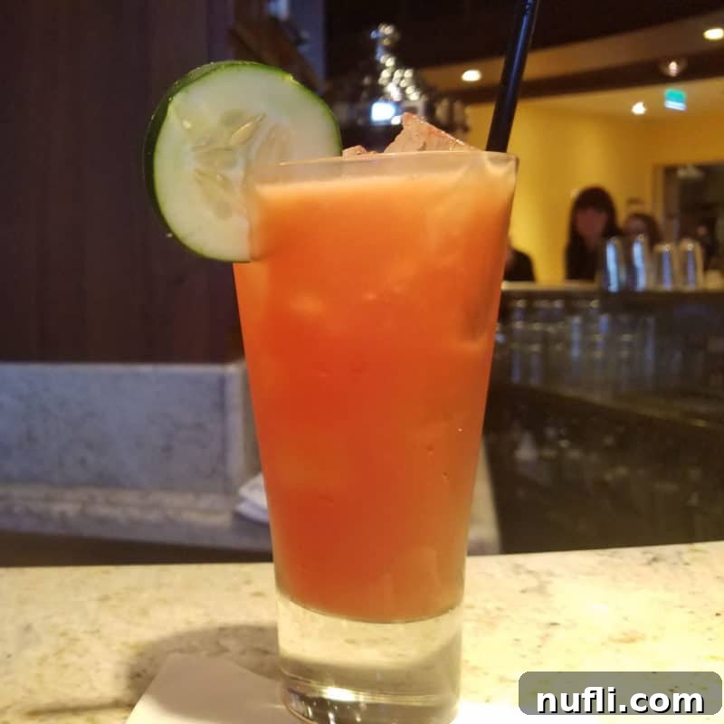 Sun-Kissed Sips: Over 35 Refreshing Summer Cocktails 38 Cucumber Sunrise in a tall glass with a cucumber wheel garnish