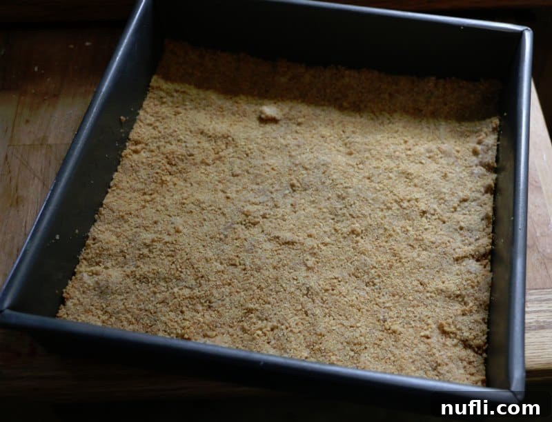 Ridiculously Easy Key Lime Bars 4 A golden-brown graham cracker crust pressed into a square baking dish, ready for the filling.