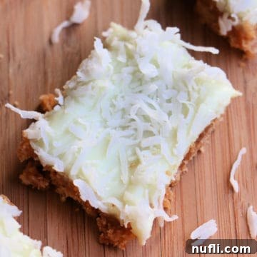 Ridiculously Easy Key Lime Bars 7 A square key lime pie bar on a wooden cutting board, showcasing its vibrant color and texture.
