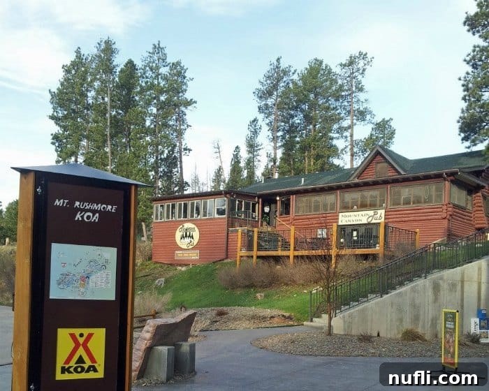 Mount Rushmore KOA sign alongside the Mountain Canyon Pub, indicating on-site dining options at Palmer Gulch