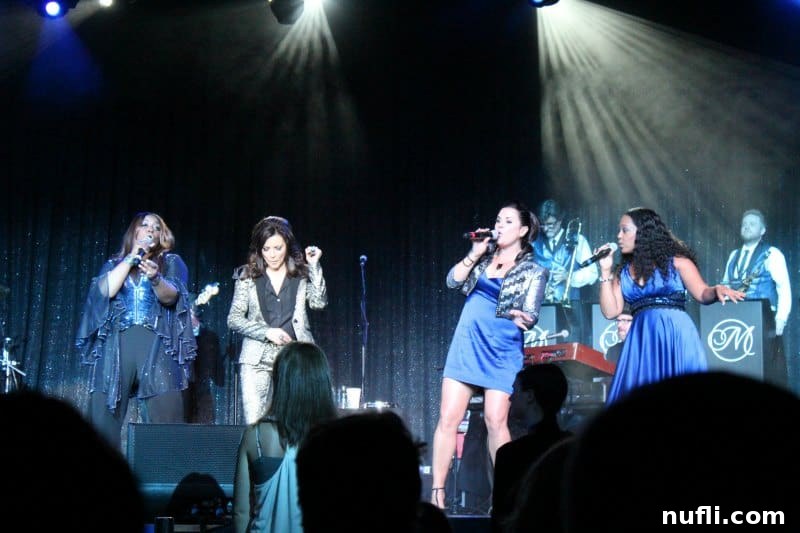 Martina McBride on stage, singing with her backup singers illuminated by stage lights
