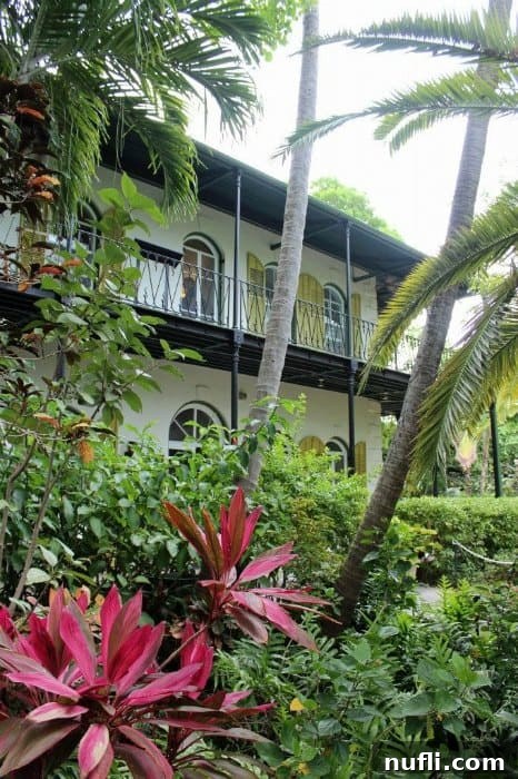 Exterior of Ernest Hemingway House with lush tropical plants and palm trees