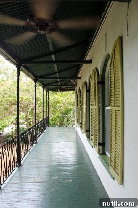 Looking down the side of the Hemingway House with green shutters on the building 
