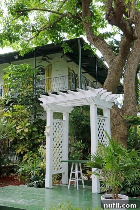 Hemingway House exterior with a large tree and a covered sitting area on the porch