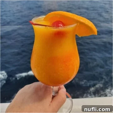 Blended kiss on the lips cocktail in a hurricane glass garnished with a cherry and orange slice