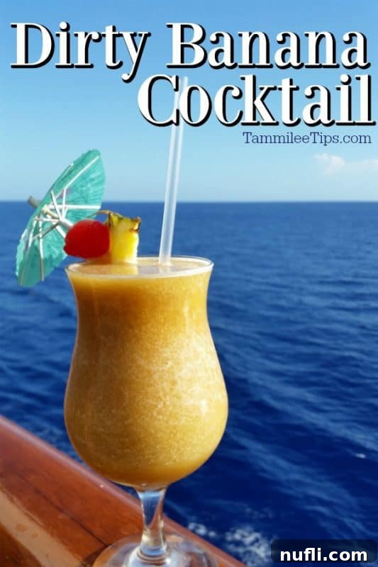 Sinfully Smooth Banana Cocktail 2 Dirty Banana Cocktail over a hurricane glass with a yellow drink, umbrella, and cherry pineapple garnish sitting on a rail with the ocean in the background.