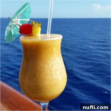 Sinfully Smooth Banana Cocktail 4 Yellow dirty banana cocktail in a hurricane glass with the ocean background