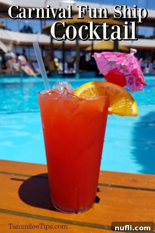 A refreshing red Carnival Fun Ship Cocktail garnished with an orange wedge, cherry, and a tropical umbrella, set against the backdrop of a cruise ship pool