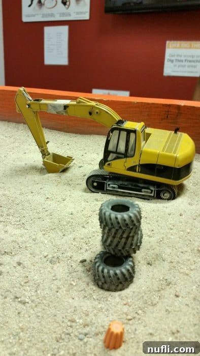 Excavator toy in a sand box with tires