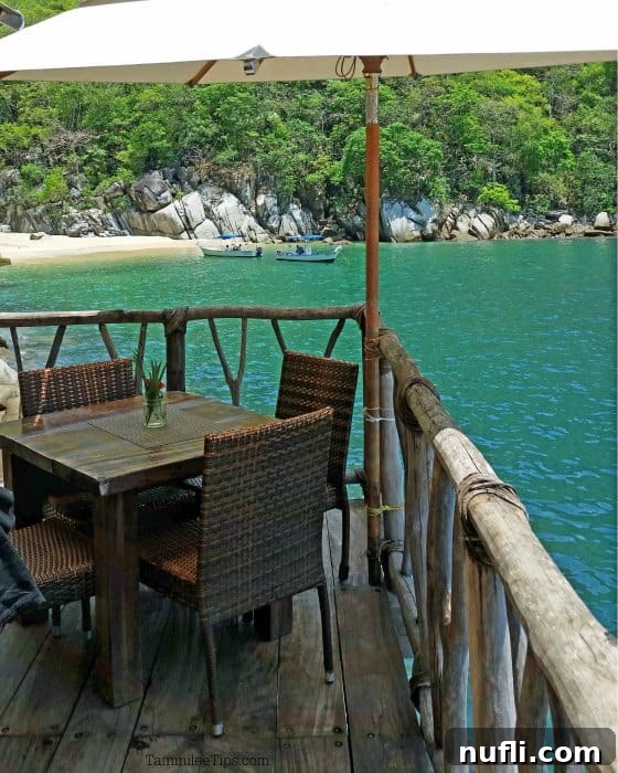 Table and chairs near a deck rail looking out over tropical beach and water