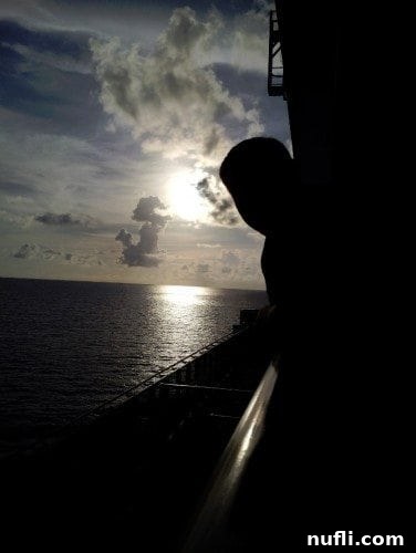 Carnival Breeze Balcony Sunset with a person leaning over the balcony, enjoying the picturesque ocean view