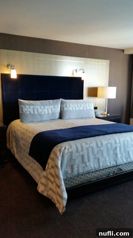 Hotel bed with lights over head and a nightstand with a lamp 