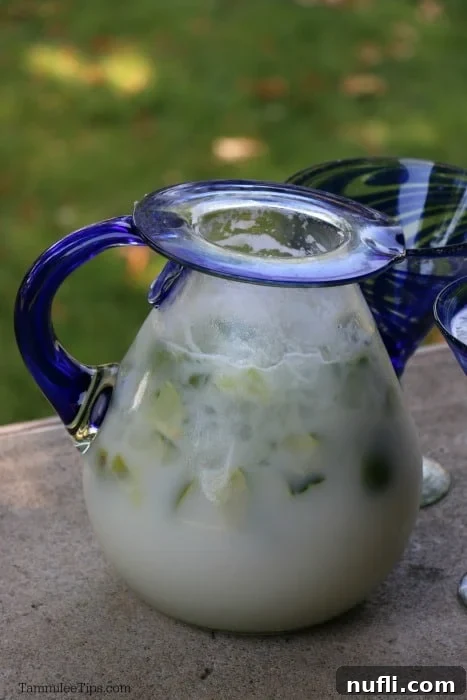 Brazilian lemonade in a glass pitcher with a blue handle. 