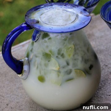 Brazilian Lemonade in a glass pitcher with limes