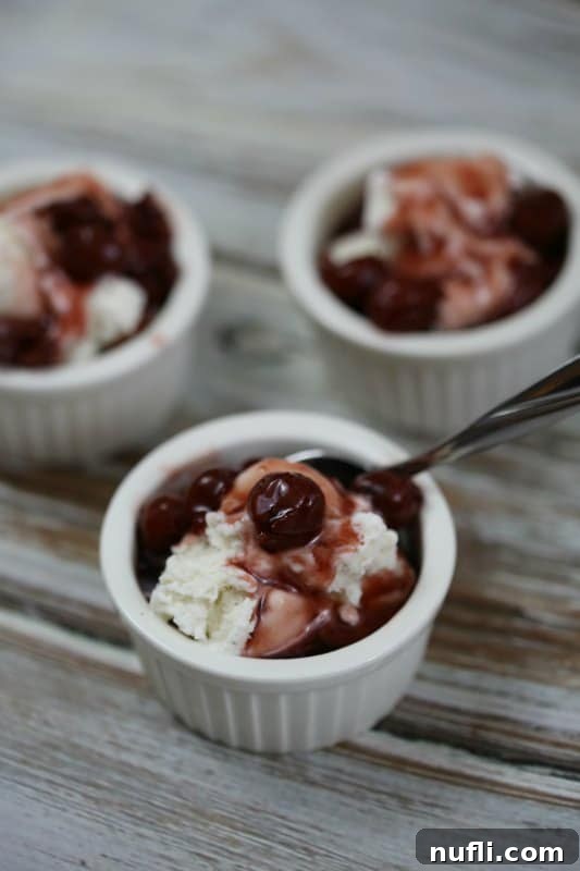 Cherry Pie Moonshine over vanilla ice cream in a small bowl with a spoon, highlighting a delicious dessert idea.