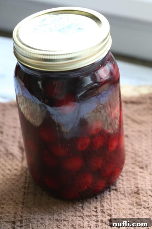 Cherry Moonshine in a sealed mason jar on a brown napkin, highlighting its rustic appeal and gift potential.