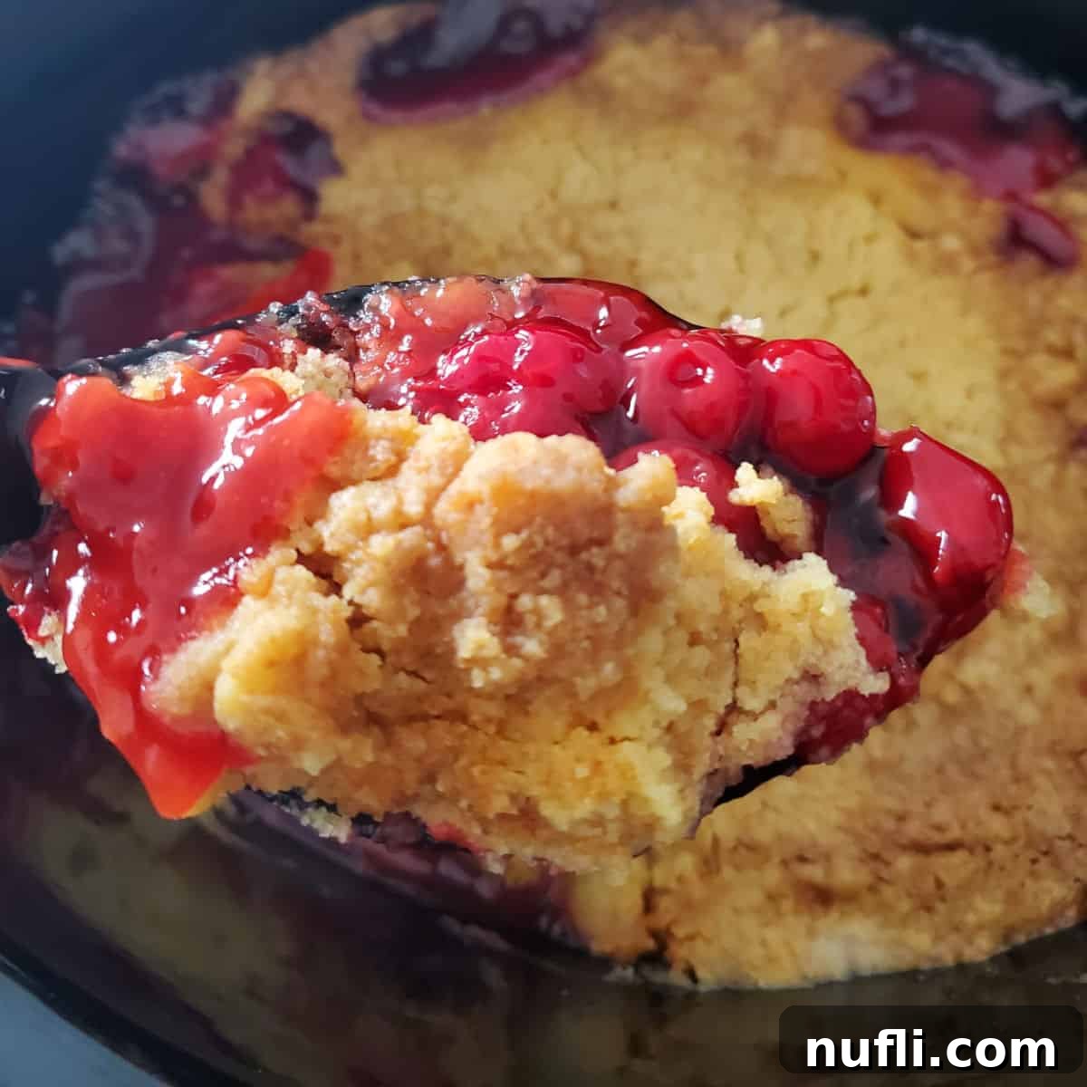 Cherry Dump Cake on a spoon above the slow cooker