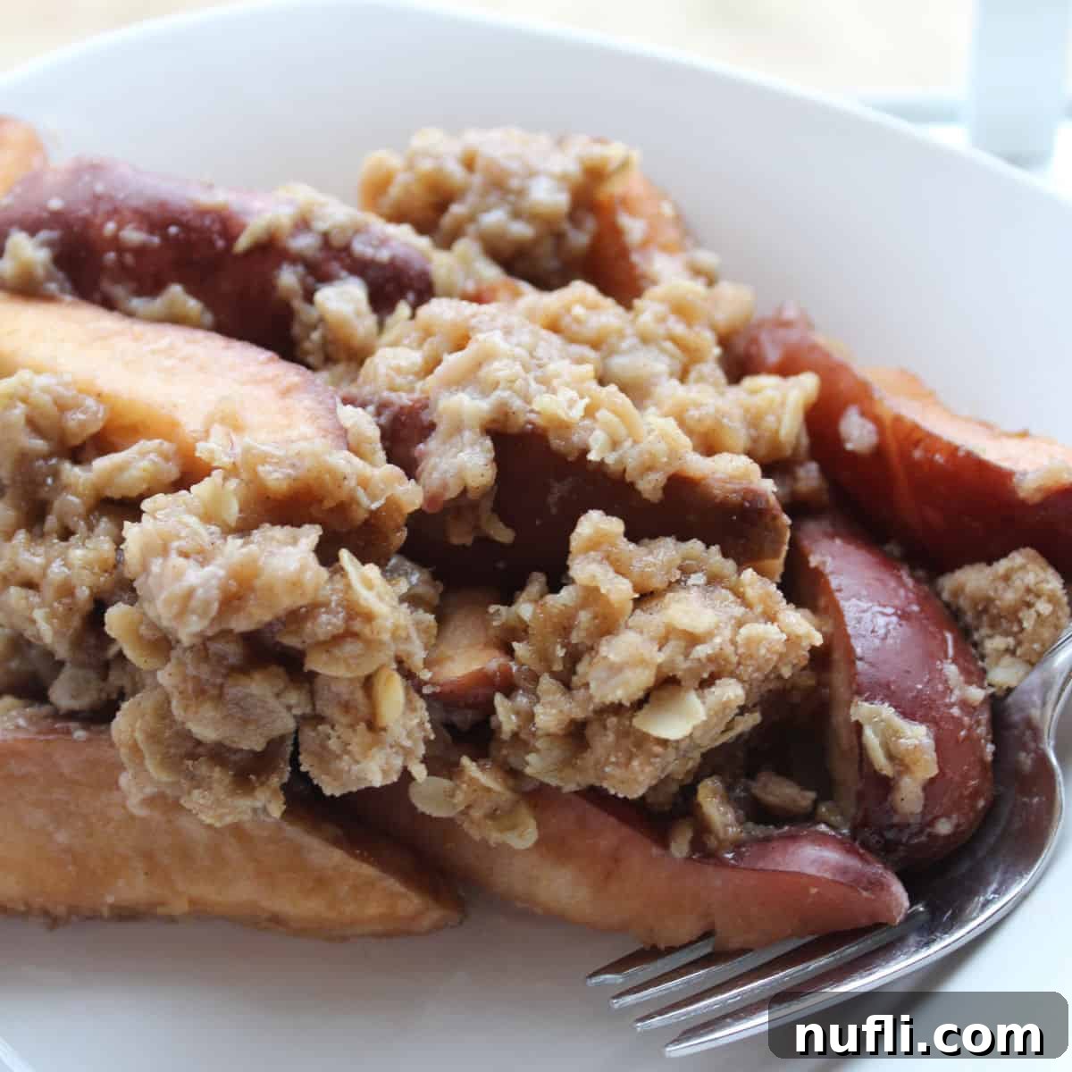 Crock Pot Apple Crisp on a white plate with a fork
