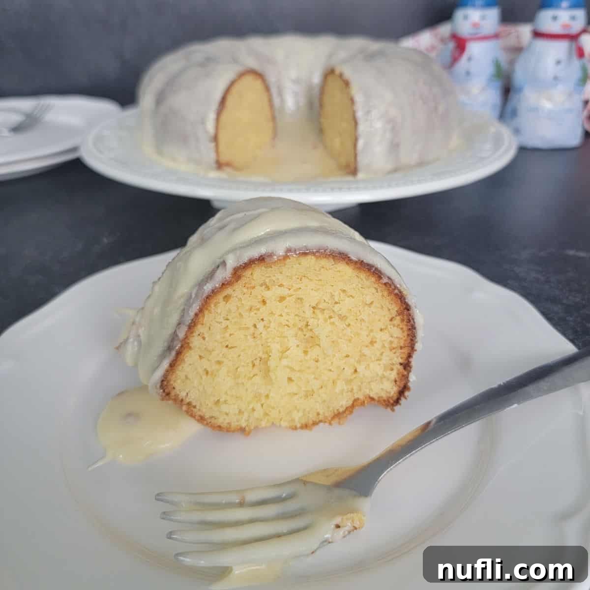 Easy Eggnog Cake with Eggnog Glaze on a white plate with a fork covered in white glaze