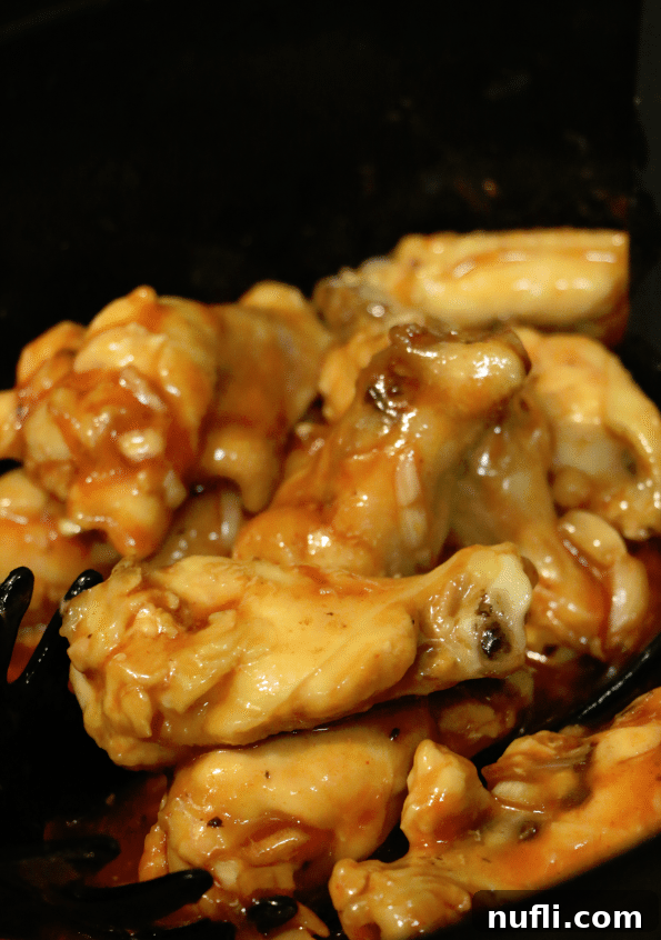 More chicken wings coated in the delicious sauce, still in the slow cooker bowl, waiting to be served.