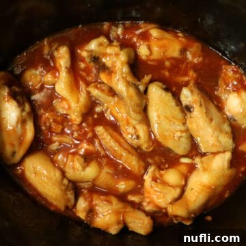 Honey Sriracha Barbecue Chicken Wings simmering in the slow cooker, glistening with sauce.