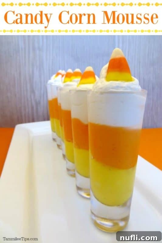 Rows of festive Candy Corn Cheesecake Mousse in shot glasses on a white platter, ready for a fall gathering