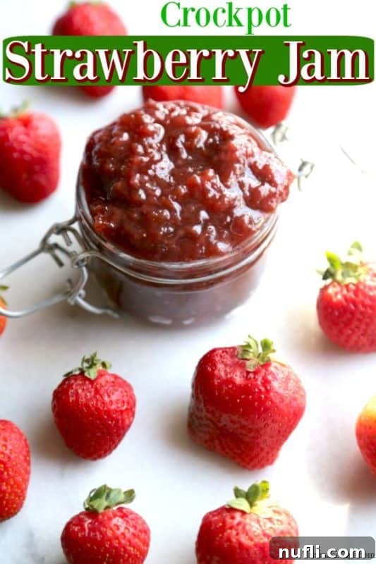 Delicious Crockpot Strawberry Jam in a glass container, surrounded by fresh strawberries.