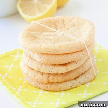 Stacked Lemon Sugar Cookies tied with twine on a yellow napkin with lemons