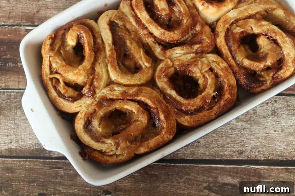 Unbaked Homemade Apple Cinnamon Rolls neatly arranged in a white baking dish, ready for the oven.
