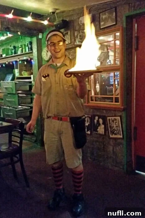 Waiter expertly serving a flaming plate of cheese in the vibrant Bubble Room
