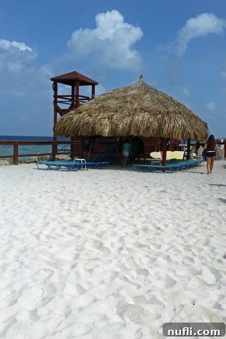 Thatch-roofed shaded area on a white sandy beach, inviting relaxation.