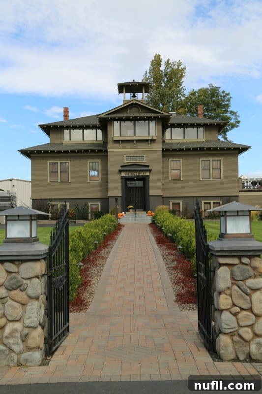 The charming and historic exterior of L'Ecole No. 41 Winery, once a 1915 schoolhouse, surrounded by vibrant green foliage under a clear sky.