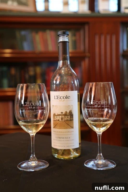 An L'Ecole wine bottle stands elegantly beside two gracefully poised wine glasses, hinting at an imminent moment of shared enjoyment and sophisticated tasting.